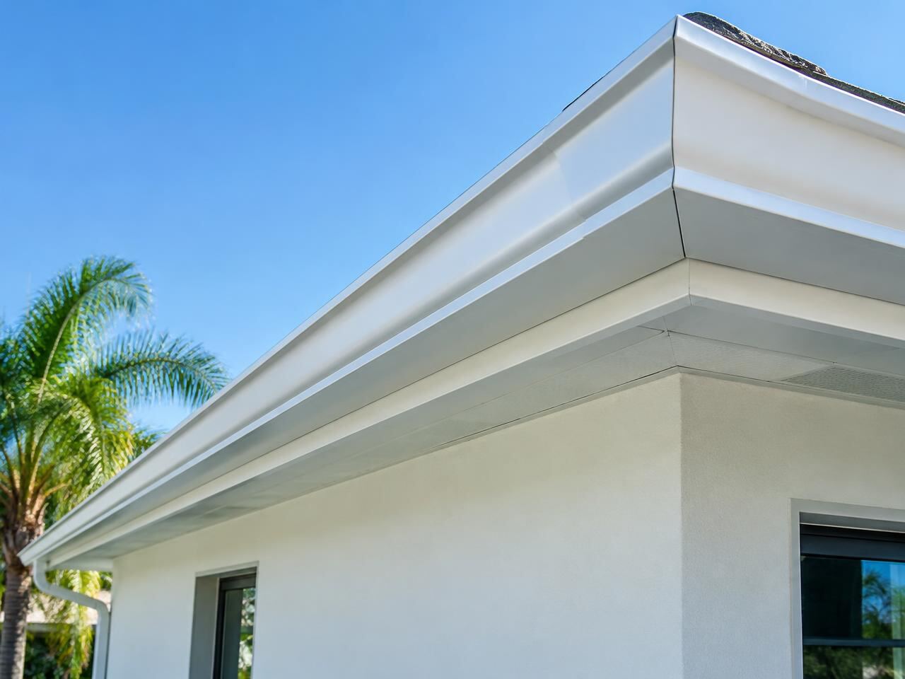 Long continuous white seamless gutter with a clean mitered corner on a stucco home